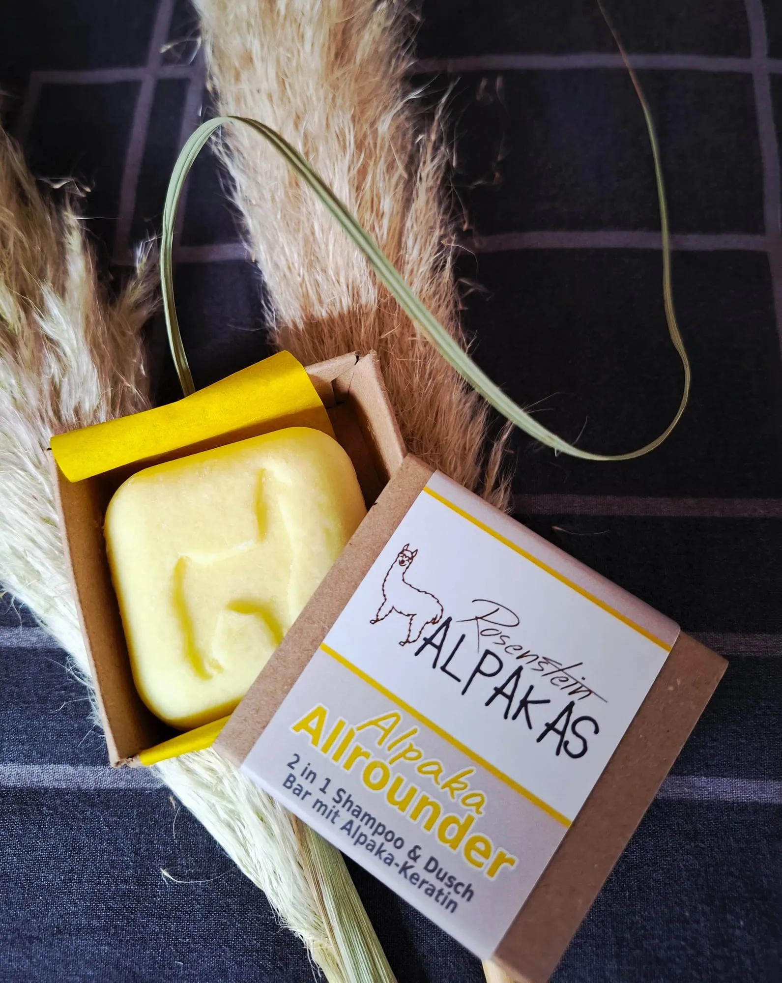Selbst gemachte Alpaka-Seife im Kraftkarton, daneben getrocknetes Pampasgras.